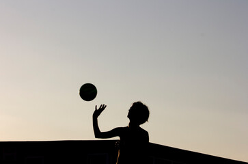 Silhouette of a girl and a ball in golden hour