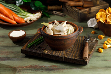 ready-made dumplings with potatoes and mushrooms in a plate on a wooden table. The wooden fork lies...