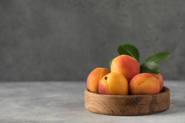  Ripe juicy apricots on a wooden plate on a gray background. Copy space