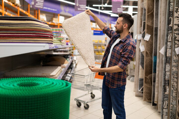 male customer in a hardware store chooses a bathroom rug