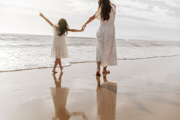 Mother and daughter admiring cloudy sky over sea