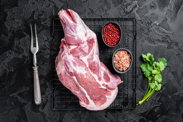 Fresh Raw lamb shoulder leg on kitchen table ready for cooking. Black background. Top view