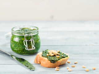 Close up view of baguette bread with fresh basil pesto sauce on gray wooden table. Copy space.
