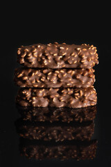 Chocolate with nuts with reflection on black background.