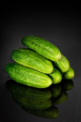 Fresh cucumbers with reflection on a black background. Organic products