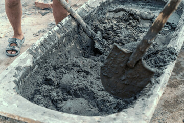 Obraz premium Workers stir or mix cement with shovels at construction site.