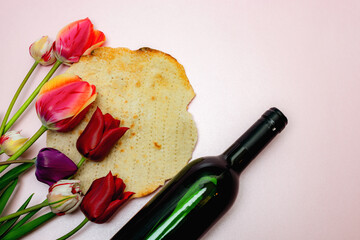 Bouquet of tulips, bottle of wine and matzo on a pink background