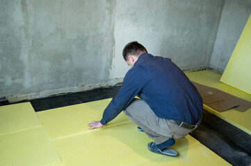 Installation of expanded polystyrene in the room for floor insulation, repair work alone, yellow...