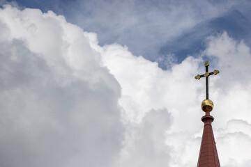 Tower of the roof of a lutheran church with a cross on the very top with beautiful thick clouds in the background Nr.2 - obrazy, fototapety, plakaty