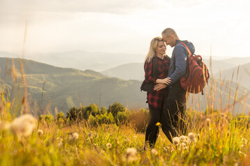 Happy traveler young couple resting in the mountains at sunset in spring or summer season.