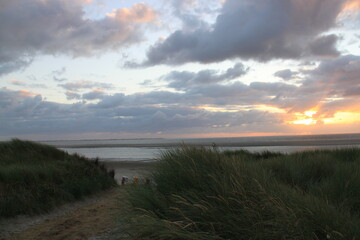 at the sea the red-golden sun shines out from behind the clouds before it sets