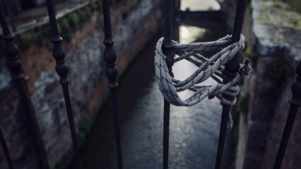 Fototapeta na wymiar A lanyard tied to a handrail against a canal in the background