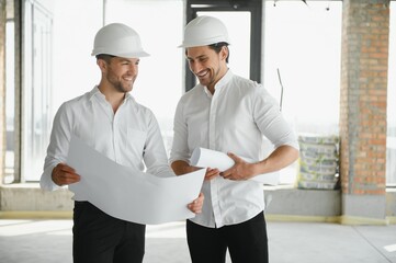 Male Architect Giving Instructions To His Foreman At Construction Site.