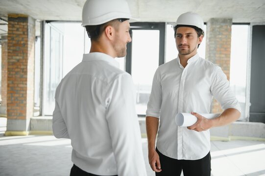 Male Architect Giving Instructions To His Foreman At Construction Site.