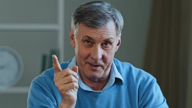 Close-up web cam view online teacher mentor old professor male portrait Caucasian elderly serious man looking camera waving shaking finger scolding explain teaching talking advice distant conversation