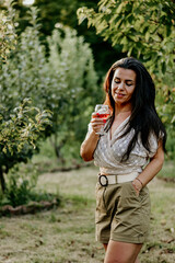 Fototapeta premium Portrait of Young Beautiful Smiling woman in a Vineyard with a glass of rose Wine. Woman enjoiyng the summer vacation