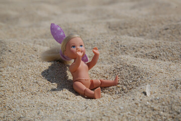Fototapeta na wymiar Little plastic doll on the sand beach