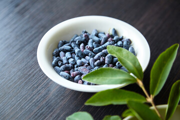 Fresh ripe honeysuckle berries in white plate over wooden table