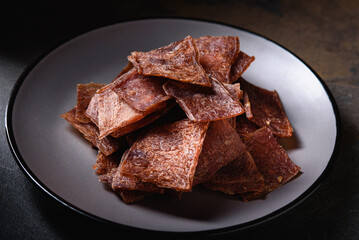 Grilled Dried Meat pieces, chips, beef, pork, chicken, lie on Gray Plate. Snack for beer.