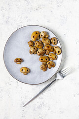 Round plate with mushrooms in the form of skulls and fork on white table. Edible Halloween Concept