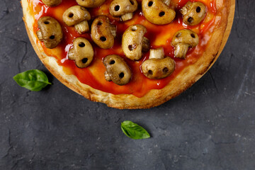 Homemade pizza with tomato sauce and mushrooms in the form of skulls. Concept for Halloween celebrations