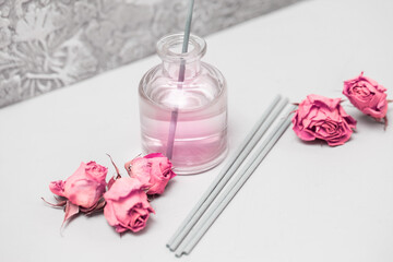 Incense sticks, dried roses and a bottle of rose water on a gray background. Products for indoor aromatization, aromatherapy and meditation