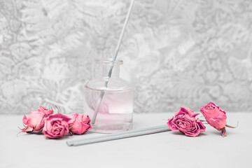 Incense sticks, dried roses and a bottle of rose water on a gray background. Products for aromatherapy and meditation. Side view