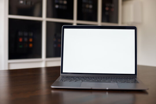 Mockup image of laptop with blank white desktop screen on a wooden table in an ordinary apartment. Laptop with blank screen for design.