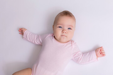 Fototapeta premium baby in a pink bodysuit is lying on the floor, top view. space for text. High quality photo