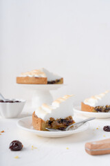 Sand cake with cherries. White background with dessert. Baking with meringue. The pie is cut.