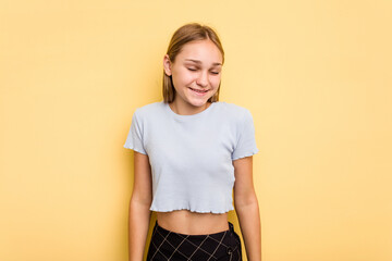 Young caucasian girl isolated on yellow background laughs and closes eyes, feels relaxed and happy.