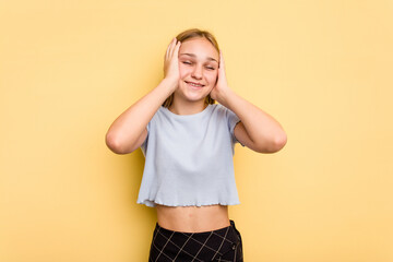 Young caucasian girl isolated on yellow background laughs joyfully keeping hands on head. Happiness concept.