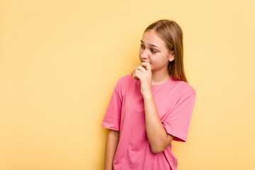 Young caucasian girl isolated on yellow background relaxed thinking about something looking at a copy space.