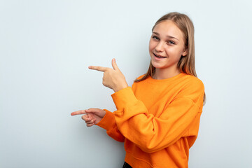 Young caucasian girl isolated on blue background excited pointing with forefingers away.