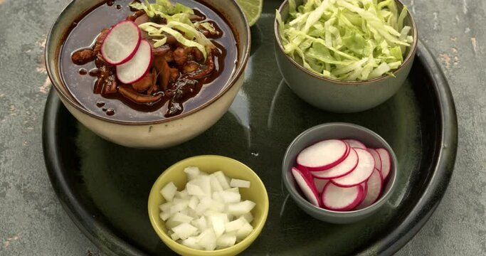 Vegan Pozole Rojo with toppings: shredded ice lettuce, radish and white onion. Famous pre-columbian  mexican dish made with cacahuazintle, shredded jackfruit, mushrooms and dried chilies.