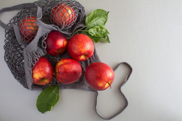 Mesh shopping  bag with red apples on the gray background.No plastic bag concept. Top view. Copy space.