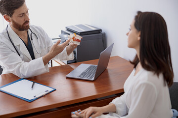 Male doctor consults patient and shows the model of several spines in modern clinic