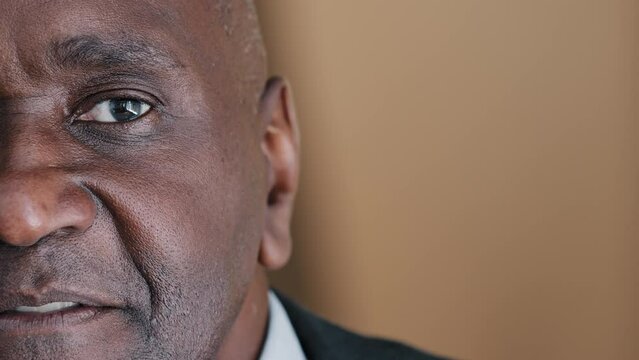 Closeup headshot half male face portrait serious mature African man middle-aged architect expert boss old elder businessman alone pensive person looking at camera, eyesight problem insurance service