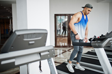 Fototapeta premium Fit and muscular arabian man running on treadmill in gym.