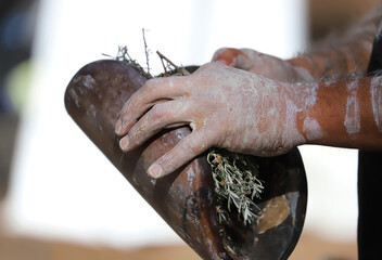 Human hands with green branches of eucalyptus and wood, the fire ritual rite at a indigenous...