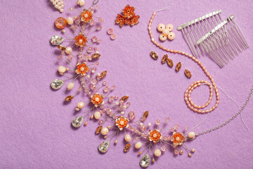 Pearls on threads, crystal beads, wire, rhinestones and other materials for jewelry on a purple background. Manufacture of fashion accessories. Copy Space