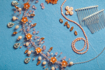 Pearls on threads, crystal beads, wire, rhinestones and other materials for jewelry on a blue background. Manufacture of fashion accessories. Copy Space