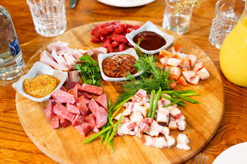 wooden dish with meat cuts, herbs, spices and sauce. 