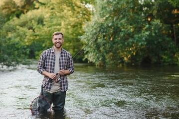 Man with fishing rod, fisherman men in river water outdoor. Catching trout fish in net. Summer fishing hobby