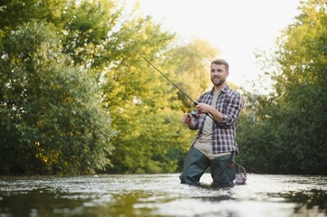 Fisherman catches a trout on the river in summer