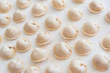 Uncooked homemade pelmeni on white table. Process of making pelmeni, ravioli or dumplings with meat