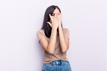 Young caucasian woman isolated on pink background blink through fingers frightened and nervous.