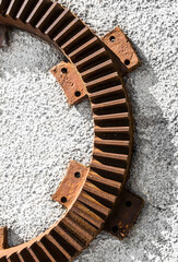 Geometric abstraction in the form of a part of a metal geared round mechanism hanging on the wall. Vertical photo