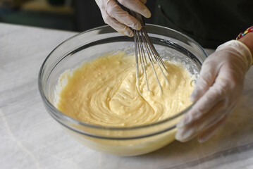 Hands in rubber gloves stirring 
dough for a cake  