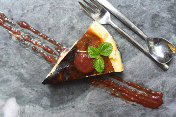 Burnt cheesecake on a stone plate with mint leaf ant toping on gray stone background top view